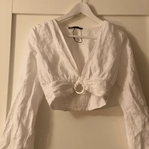 ZARA festlig topp  - En topp i en v-ringad modell. Använd ett par fåtal gången. Vit färg med en fin silverring under bröstet. 