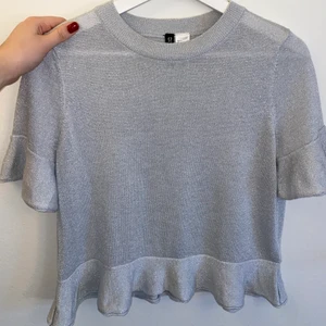 Glitter topp  - Säljer min glittriga topp med volang pga för liten. Fint stickad med glitter i. Funkar till vardags och fest. Lite kortare i modellen. Fraktar endast och köparen står för frakten🖤