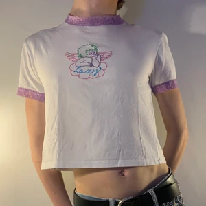 Vit baby tee lazy oaf brodyr lila spets - vit baby tee/croptop från Lazy Oaf med en broderad ängel i grön, lila och rosa och texten Lazy i blått samt med lila spets vid ärmarna och halsen 🌨 Den är märkt som en storlek 12, men jag skulle uppskatta den som en vanlig S-M men är otroligt stretchig! Eftersom tröjan har så många färger kan man gå all in med att matcha den med ett par byxor och accessoarer i samma färger eller bara med ett par jeans för en chill outfit!