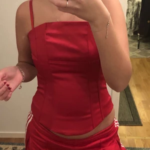 Topp i röd - Lite av en blanding mellan korsetttop och vanlig topp. Väldigt fin topp i röd färg med superfint material. Passar till utekväll eller bara en middag. Säljes pga den inte kommer till användning:(