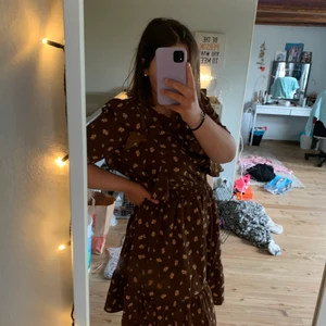 Blommig klänning  - Blommig brun somrig klänning med volanger🌸🐬☀️🍉🍭🐚🌻👙👗Passar både S och L!