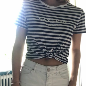 Blå-vitrandig topp  - En blå-vitrandig (mörkblå) topp från H&M. Den har en kort passform och sitter bra kring axlar och följer kroppens former! Knytning på magen och ett tryck över bröstet: SAN FRAN U.S.A. Luftig och fin till sommaren☀️ Storlek S och knappt använd så den är i gott skick:)