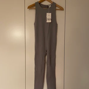Zara jumpsuit  - Helt ny, endast provad. Grå/lila tajt jumpsuit från Zara i storlek M-L. Stretchig och ganska tjockt material, tajt.