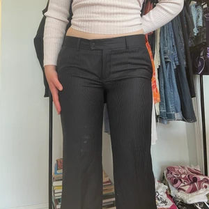 Lågmidjade kostymbyxor - Trendiga kostymbyxor med vita smala ränder! Lågmidjade och sitter som en smäck på s/m....Passar bra i längd på mig som är 173 men passar absolut kortare också. Hör av er för frågor!