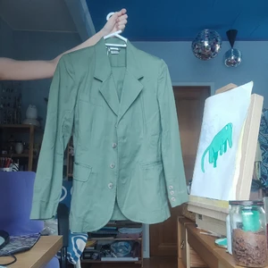 Grönt är av kavaj + kjol - Kostym bestående av en fitted kavaj med A-line kjol. Kjolen hänger där i. 
