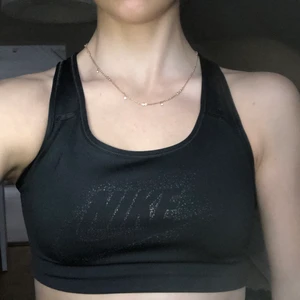 Nike sporttopp strl. S - Svart sporttopp från Nike i strl. S. Inte vadderad. Nikeloggan är tryckt i glittrigt silver. Är i mycket bra skick!! Gratis frakt.