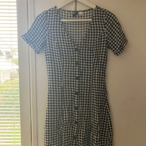 Rutig kort klänning - Jag har tyvärr ingen bild på hur den sitter på kroppen. Men den är i ett skjort material och den är rätt kort. Jag är 170cm och den slutar på mitten av låren. Jag betalar tyvärr inte frakten.