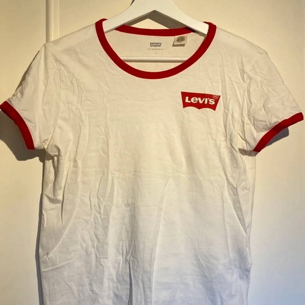 En vit Levis t-shirt med röda detaljer, är i bra skick. Dock lite genomskinlig. Köparen står för frakt, betalning sker via swish. T-shirts.