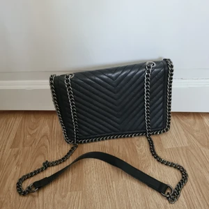 Svart väska - Svart väska med kedjedetaljer. Ungefär 30 cm lång och 20 cm hög.