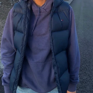Väst Tommy Hilfiger  - Säljer en jättefin och trendig väst ifrån Tommy Hilfiger💘västen är mörkblå och i storlek 152 men sitter som en xs💙lite rött och vitt på luvan, den är använd men i mycket bra skick!!