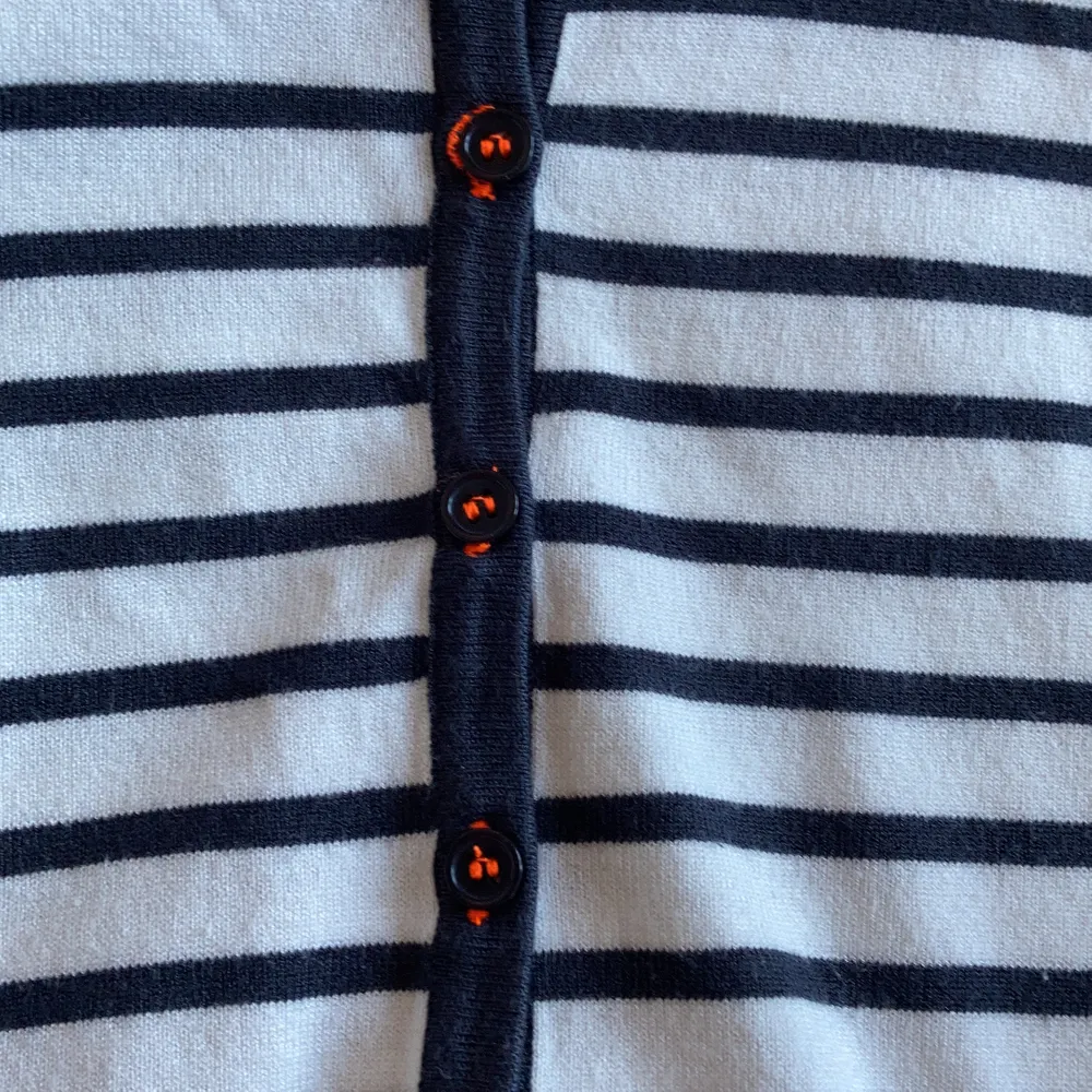 Svart o vit randig tröja med orangea detaljer runt knapparna. Använd fåtal ggr. Tjockt o fint material. . Skjortor.