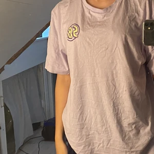 Lila t-shirt  - Lila t-shirt från H&M med tryck på baksidan. Köpt för 170. Frakt ingår inte
