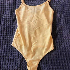 Gul body  - Gul body med spänn band. Ganska liten i storlek så passar även xs 