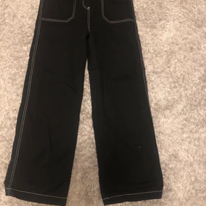 Svarta byxor med vita sömmar - Svarta vida byxor med vita sömmar från junkyard, köpta för ca. 2 år sen men knappt använda. Nypris ungefär 270kr. Köpare står för frakt.