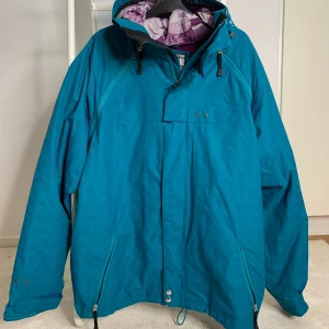Oakley skidjacka i cyanblå  - En skidjacka använt Max 10 skiddagar. Strl L och modellen är Loose fit. Ventilationsdragkedja under armhålorna, två ytterfickor och två innerfickor. Den är lätt fodrad och vid kallare skiddagar krävs en tjocktröja. Eventuell frakt betalas av köpare. 