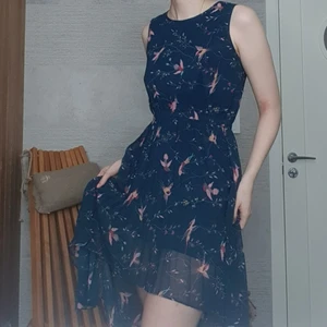 Blå Klänning - Blå klänning med fågel mönster, som är kort fram och lång bak, Storlek M men passar som S också.
