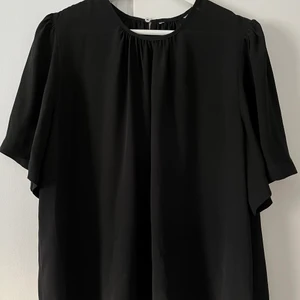 Blus med puffärm, strl 44 - En supersöt svart blus med puffärmar. Strl. 44 men avslappnad i modellen. 
