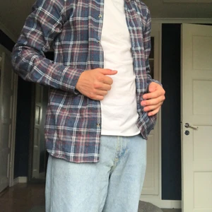 Flanellskjorta  - Mörkblå flanellskjorta med röda och vita linjer. Det är storlek S och säljer den för 150 kr + frakt.