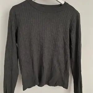 En grå ribbad tröja med detajl vid midjan🤍
