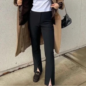 Kostymbyxor med slits - Kostymbyxor med slits från NA-KD. Lite noppriga därav det billiga priset men inget som märks. Väldigt bekväma!