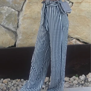 Byxor  - Säljer mina svart och vit randiga byxor som är vida och perfekta till sommaren. Stretchiga och justerbara i midjan. Från mango. Finns fickor! 