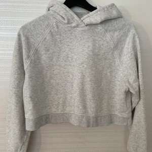 Grå Croppad Hoodie - En ljusgrå croppad hoodie. En väldigt basic men underskattad plagg i garderoben, perfekt till Jeans eller liknande! Använd men i bra skick, inga defekter eller fläckar!