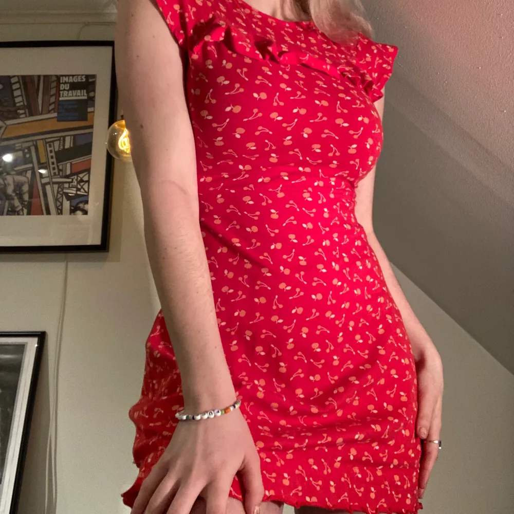 Röd klänning med volanger och körsbärsmönster, tight modell som är supersöt<3 från märket tyska märket  blutsgeschwister. Storlek XS men stretchtyg!! Köparen står för frakt . Klänningar.