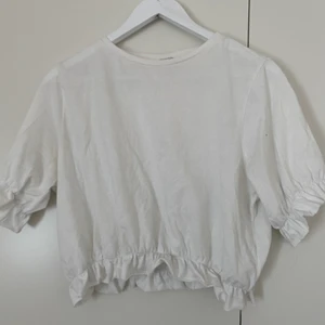 Vit t-shirt med lite volang! 🌴 - STORLEK: M | SKICK: Använd | Söt vit T-shirt med lite volang på ärmarna och i midjan! Använd fåtal gånger, köpt förra året 🦔