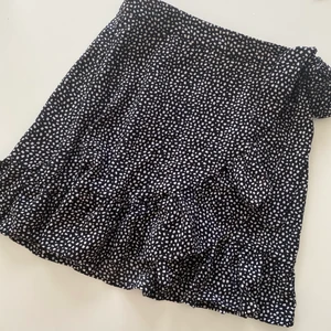 Prickig volangkjol - Så fin volangkjol i ett prickigt mönster. Den har en dragkedja på sidan vilket gör att den är enklare att ta på sig då man ej själv behöver knyta den omlott. Är använd få gånger då den är lite för liten för mig. Kontakta mig vid fler bilder/frågor, frakt tillkommer. 