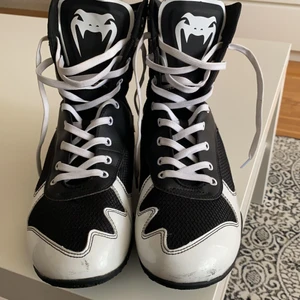 Ett par boxnings Venum skor. Jätte sköna och går för bra pris  - I salu är det ett par venum boxningsskor svart vita, jätte snygga. Är i storlek 43. Säljs för bra pris är väldigt dyra i butiker. Köpta för inte så länge sen använda ett par gånger men de ser helt nya ut förutom lite skrap märken på bilden som ni ser. Dessa skor är perfekta för boxnings intresserade människor som behöver sköna och skickliga skor att träna med och tävla med.