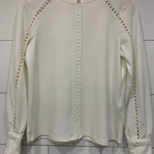 White  Blouse  - Blouse in jersey crêpe with inset lace trims, a round neckline and a small opening with shimmering gold button at the back of the neck. Long sleeves and wide cuffs with concealed press-studs.