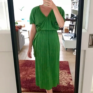 Plisserad klänning  - Finplisserad klänning i en härligt poppig grön färg med omlott detalj i sidan. Från asos i storlek EU32. Kan skicka icke-spårbart om billigare frakt önskas. 