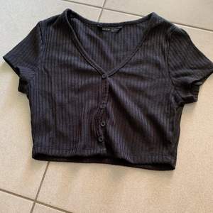 En svart T-shirt från SHEIN med knappar. Helt oanvänd 