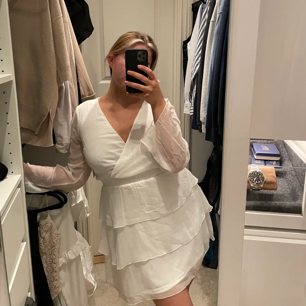 En vit klänning med volanger. Klänningens längd är till mitten av låret på mig som är 168 cm lång. Klänningen har aldrig använts. . Klänningar.