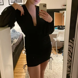 Svart festklänning i mesh - Riktigt snygg klänning, mesharmar, vringas, söm i mitten på röven, dragsko på båda sidorna av höften. 