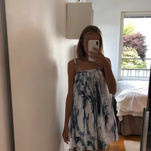 HowToKissAFrog klänning - CONI DRESS IN MINTWATER                                                    Vit klänning med mönster av blått vattenskvätt. Knytbara axelband med blå och vita pärlor på. Lös passform. Köpare står för frakten.