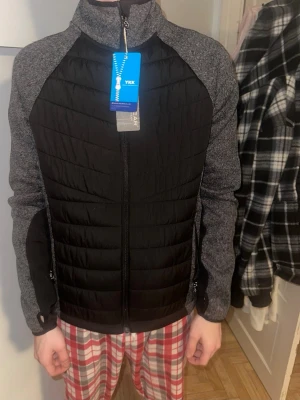 Svart och grå jacka ifrån bluewear  - Snygg jacka med svart quiltad front och rygg samt gråmelerade ärmar och sidor. Den är helt oanvänd och har lappen kvar 