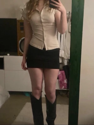 Beige kortärmad blus med knappar - Snygg beige blus med korta ärmar och figurnära passform. Blusen har klassisk krage och knäppning framtill, vilket ger en stilren och enkel look. Perfekt att matcha med kjol eller jeans för en trendig outfit.(Säljer min kompis kläder) jätte fin lappen är bortklippt.