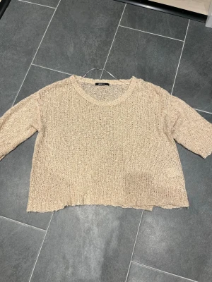 Beige stickad tröja från Gina Tricot - Säljer en rosa/beige stickad tröja från Gina Tricot i storlek S. Tröjan har en lös passform, rund halsringning och är tillverkad i ett grovt stickat material med struktur. Perfekt för att skapa en avslappnad och trendig look. 