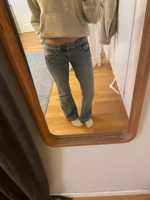 Blå bootcut jeans med låg midja - Säljer ett par blå bootcut jeans med låg midja och klassiska fem fickor. Jeansen har snygga detaljer på bakfickorna och är i ett mjukt denimtyg. Perfekta för en avslappnad och trendig look. Strl 158 men är 163 och de passar bra.