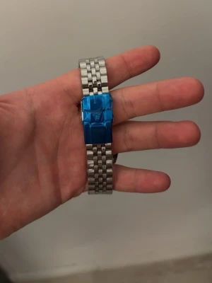 Rolle klocka - Stilren klocka från R med länkarmband i rostfritt stål och klassisk silverfärg. Spännet har en blå skyddsfilm och märkets logga syns tydligt. Perfekt accessoar för dig som gillar en clean och modern look samt pris går att diskutera tveka ej angående frågor osv! Den är fortfarande plastat och är i nyskick.