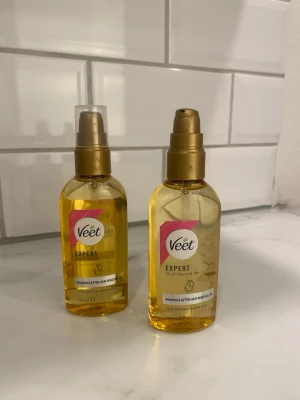Veet Expert Multi-Benefit Oil - Två flaskor Veet Expert Multi-Benefit Oil med pump, perfekt för rakning och efter hårborttagning. Oljan är guldfärgad och kommer i genomskinliga plastflaskor med guldlock. Innehåller 100% naturliga oljor och har en smidig sprayfunktion.