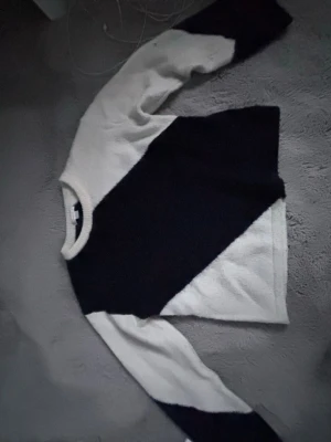 Svartvit stickad tröja Gina Tricot - Snygg stickad tröja från Gina Tricot i svart och vitt med coolt diagonalt färgblocksmönster. Tröjan har rund halsringning och långa ärmar. Perfekt för dig som gillar en stilren men trendig look.