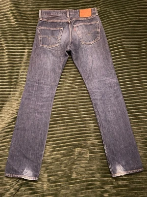 Levi's raka blå jeans - Klassiska blå jeans från Levi's med rak passform och fem fickor. Tillverkade i slitstark denim med den ikoniska röda Levi's-lappen på bakfickan.
