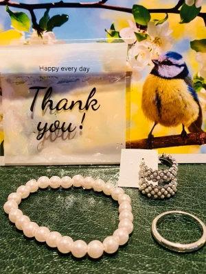 Fina bijouterier  - Säljer ett stilrent armband med vita, runda pärlor trädda på elastisk tråd. Perfekt accessoar för att lyfta din outfit med en tidlös och elegant touch. Passar dig som gillar klassiska smycken med enkel design.Matchande örhängen  samt stilrent silverring i stainless steel. 