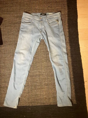 Replay anbass  - Säljer ett par ljusblå skinny jeans från Replay med klassisk femficksdesign och guldfärgade detaljer. Jeansen har en snygg tvätt och är tillverkade i mjukt denimtyg som sitter tight hela vägen ner. Perfekta för dig som gillar en slim och modern look.