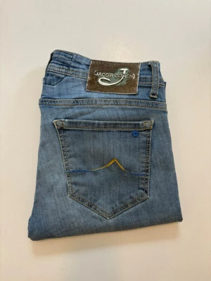 Jacob Cohen jeans limited edtion - Blåa Jacob Cohen jeans limited edition //  Modell: 688  Mycket bra skick endast några små slitningar vid knäna som syns på bilderna //  Storlek 33 //  Mått Midja bredd 41cm  Längd 107cm Innerben längd 80cm  Lårvidd 27cm  Benöppning 18 cm  Skriv vid minsta fråga eller fundering🤝 