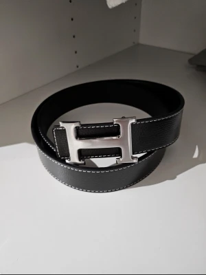 Svart H bälte - Svart H-bälte i mycket fint skick. Stilrent och trendigt – en perfekt accessoar som ger outfiten det lilla extra. Hör av dig vid intresse.