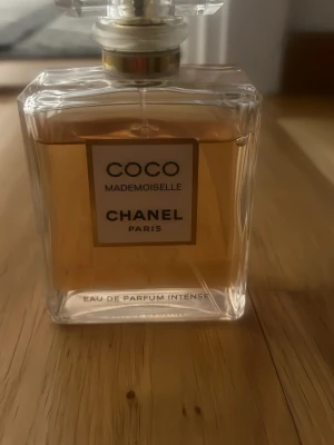 Coco Mademoiselle Eau de Parfum Intense - Coco Mademoiselle Eau de Parfum Intense från Chanel är en elegant parfym i en klassisk, fyrkantig glasflaska med guld- och vit etikett. Doften har en varm bärnstensfärgad vätska och flaskan har en exklusiv, genomskinlig kork.