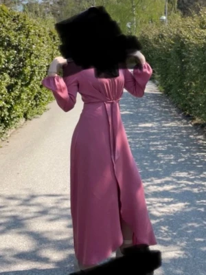 Lång rosa/lila omlottklänning med knyt - Snygg långklänning i lila med omlottmodell och knyt i midjan. Storlek S. Den har en fin slits. 